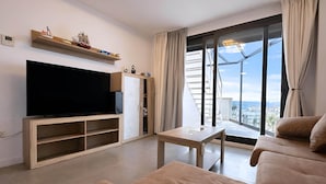 A modern living room with a flat-screen TV, a sofa, a coffee table, and a large window with a view. - Marinsa Beach - Penthouse (Torrox)