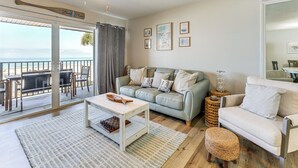 Un salon avec un canapé, une table basse, un jeu d’échecs et un balcon offrant une vue agréable.
