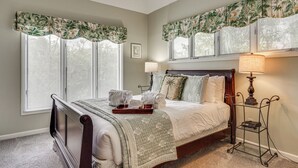 A bedroom with a bed, a nightstand, a lamp, and a window with blinds. - Enjoy Coastal Living! Condo on Kiawah Island (Kiawah Island)