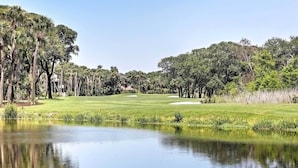 A golf course with a pond in the foreground, surrounded by trees and a clear sky. - Enjoy Coastal Living! Condo on Kiawah Island (Kiawah Island)