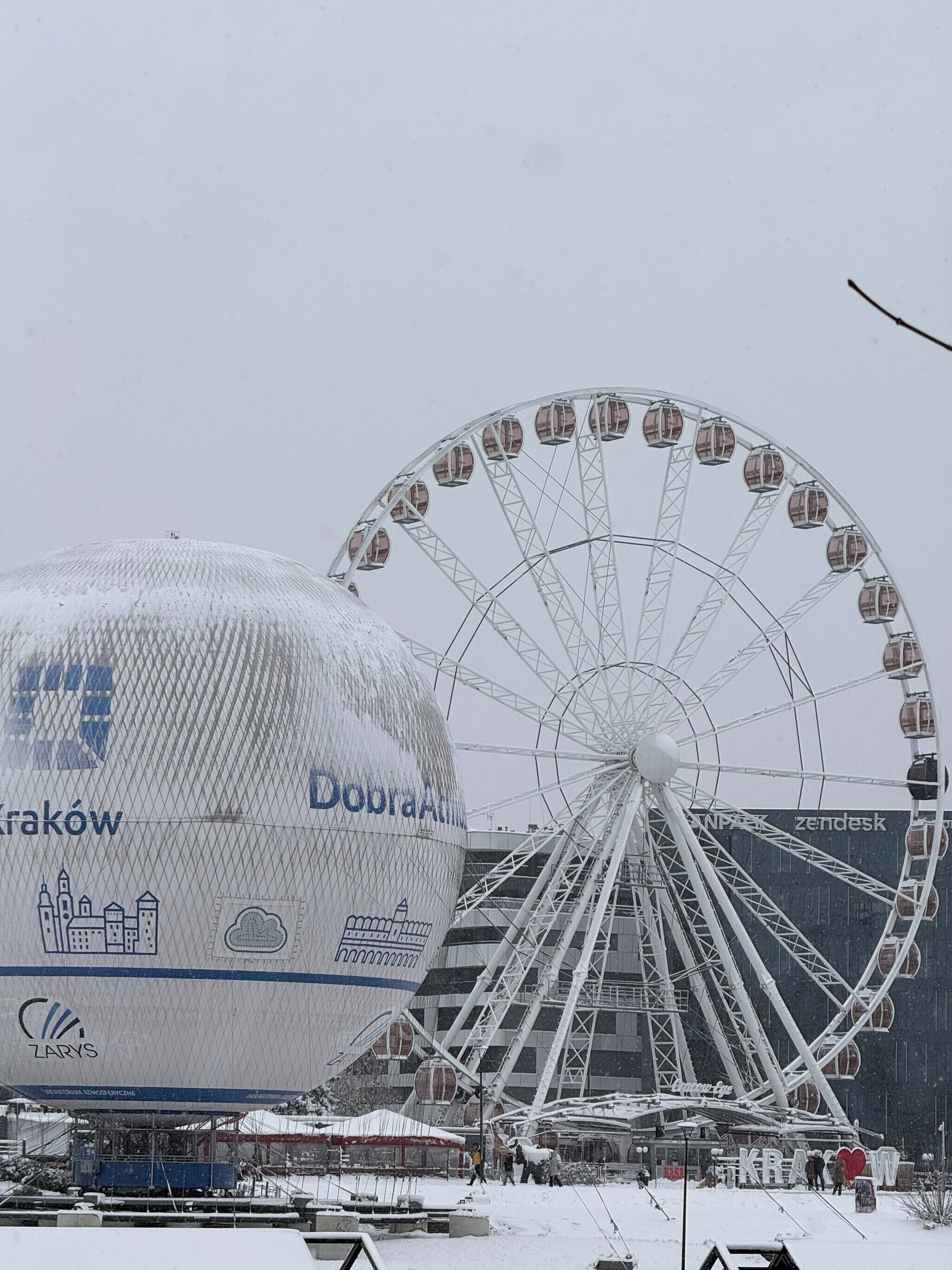 Eine große, kugelförmige Struktur mit der Aufschrift 'DobraAt' und ein Riesenrad mit Gondeln.