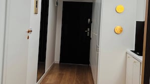 A hallway with a skylight, wooden flooring, white walls, and a black door at the end. - The Perfect Cozy Oasis (Kraków)