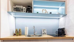 A kitchen with a stainless steel sink, a coffee machine, and a shelf with decorative items. - The Perfect Cozy Oasis (Kraków)