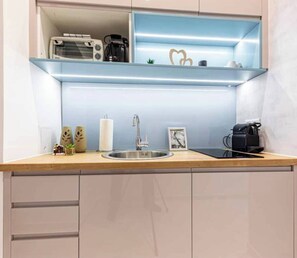 A kitchen with a stainless steel sink, a coffee machine, and a shelf with decorative items. - The Perfect Cozy Oasis (Kraków)