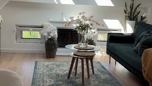 A modern living room with skylights, a fireplace, and a green sofa. - The Perfect Cozy Oasis (Kraków)