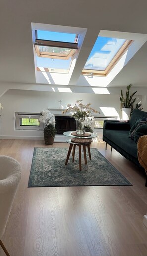 A modern living room with skylights, a fireplace, and a green sofa. - The Perfect Cozy Oasis (Kraków)