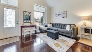 A living room with a grey sofa, a patterned rug, a wooden bench, and a small table with a lamp. - Patio Oasis! Contemporary Tacoma Hideout (Tacoma)