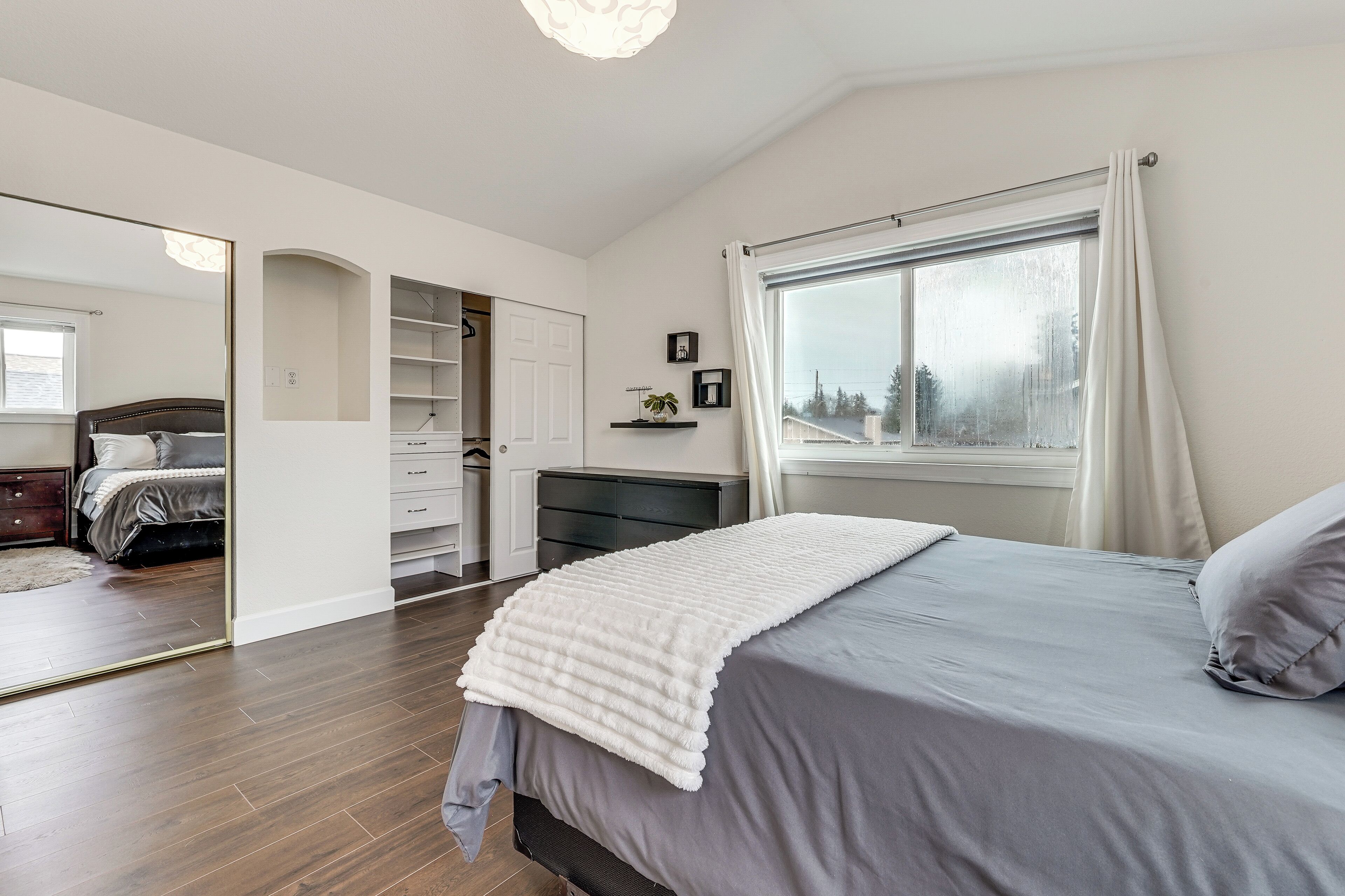 A bedroom with a bed, a wardrobe, a desk, and a window.