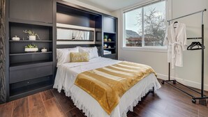 A bedroom with a bed, built-in shelving, a window, and a walk-in closet. - Patio Oasis! Contemporary Tacoma Hideout (Tacoma)