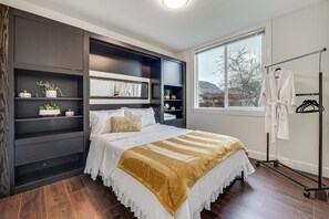 Ein Schlafzimmer mit Bett, Einbauschränken, einem Fenster und einem begehbaren Kleiderschrank.