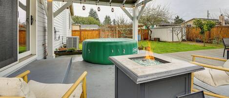 A covered patio with a fire pit, outdoor seating, and a green inflatable pool.