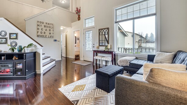 A spacious living room with a staircase, a large window, and a chandelier. - Patio Oasis! Contemporary Tacoma Hideout (Tacoma)