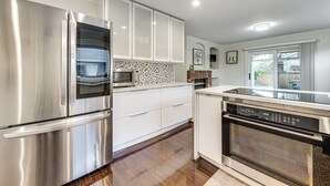 A modern kitchen with stainless steel appliances, white cabinetry, and a patterned backsplash. - Patio Oasis! Contemporary Tacoma Hideout (Tacoma)