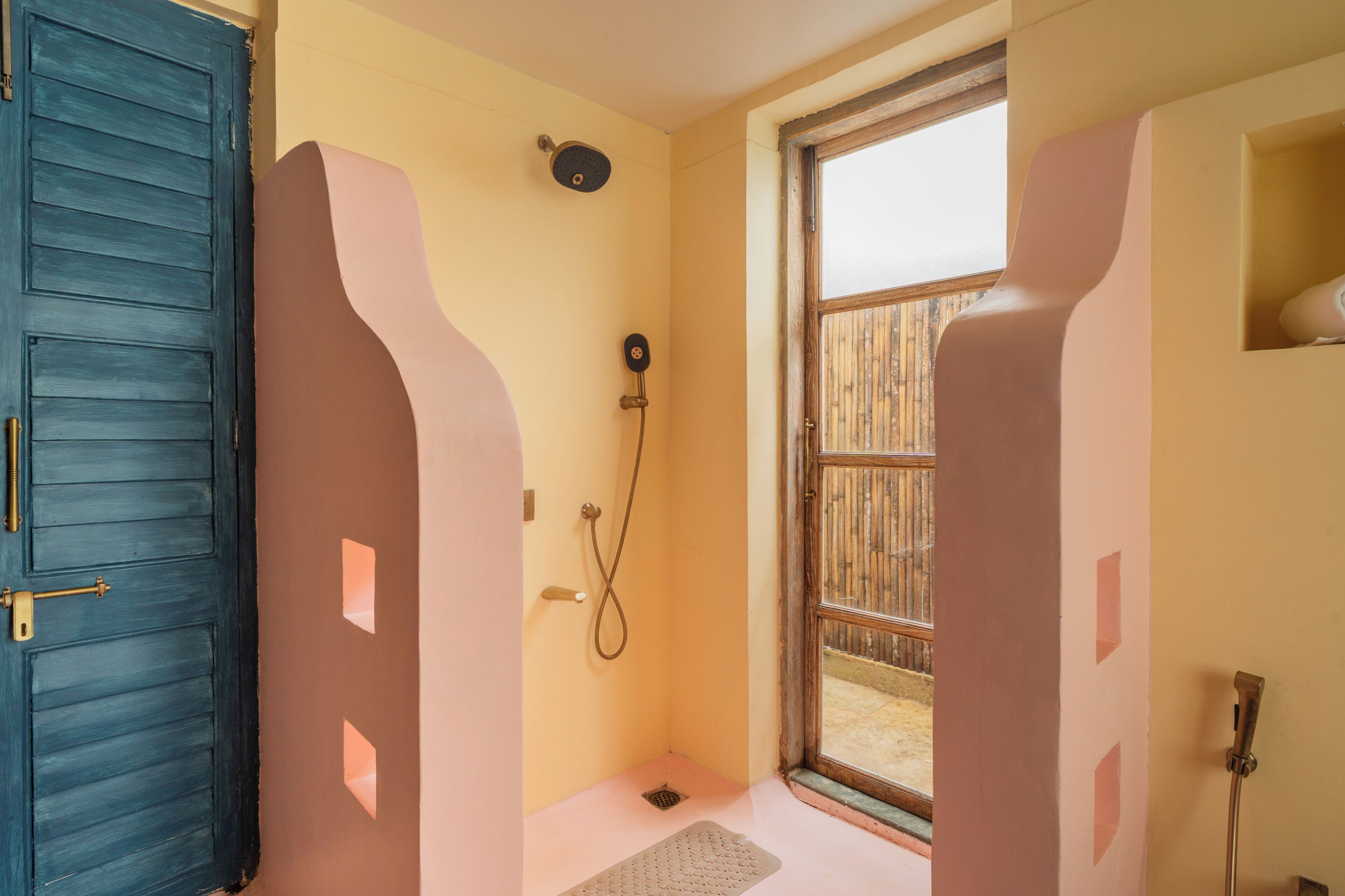 A bathroom with a shower, a door, and a window.