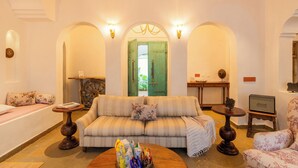 A living room with a sofa, armchairs, a coffee table, and a view through an arched doorway. - ELIVAAS Amayah Rasa 4 BHK Villa (Assagao)