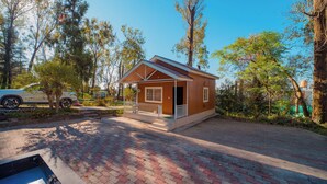 A small, single-story building with a porch, surrounded by trees and a paved driveway. - Forest Rest House Bir (Bir)