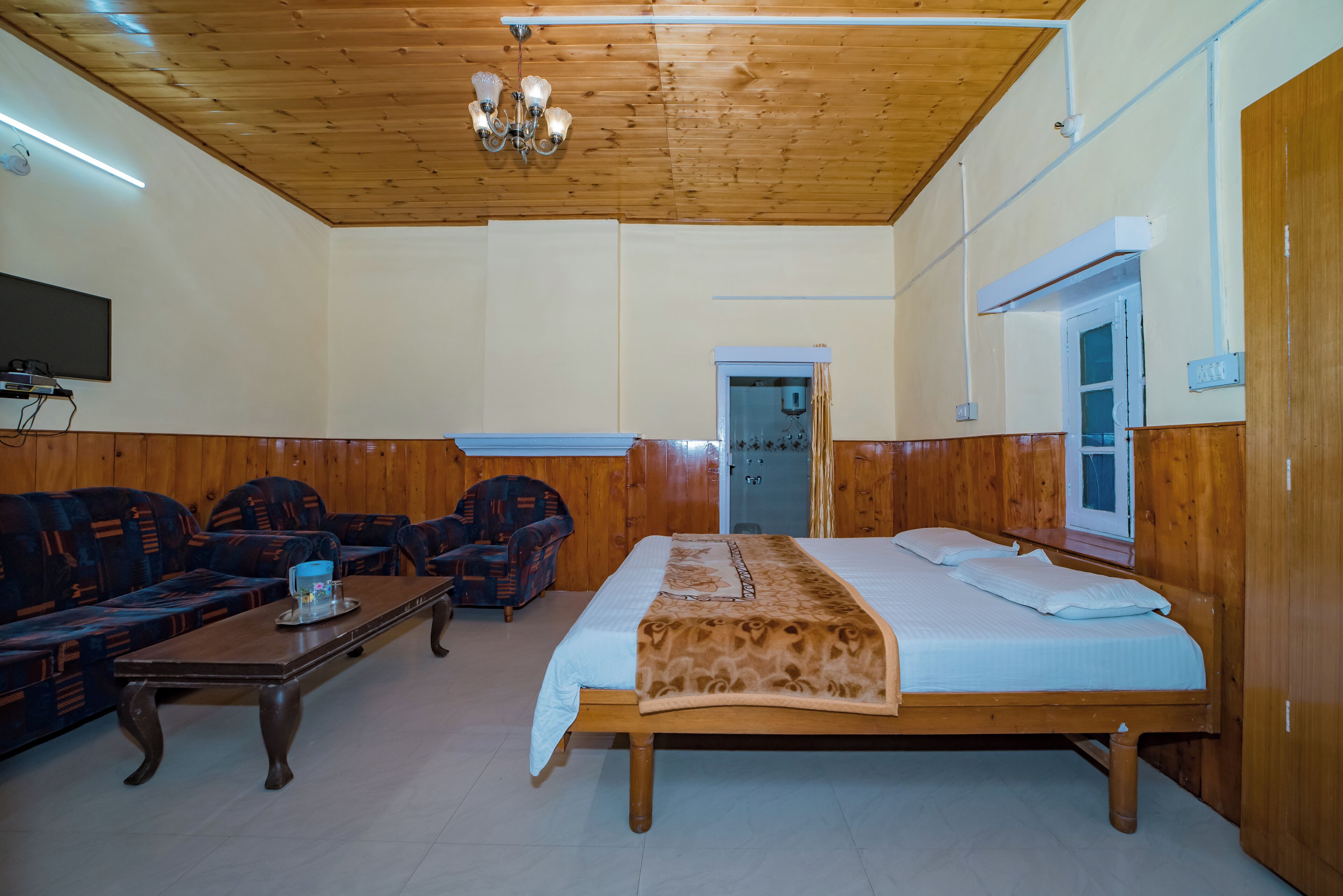 Una habitación con cama, sofá, mesa de centro y televisión.