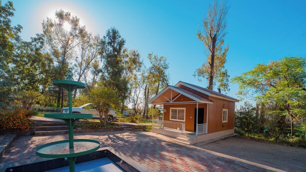 A small house with a porch, a fountain, and a paved driveway. - Forest Rest House Bir (Bir)