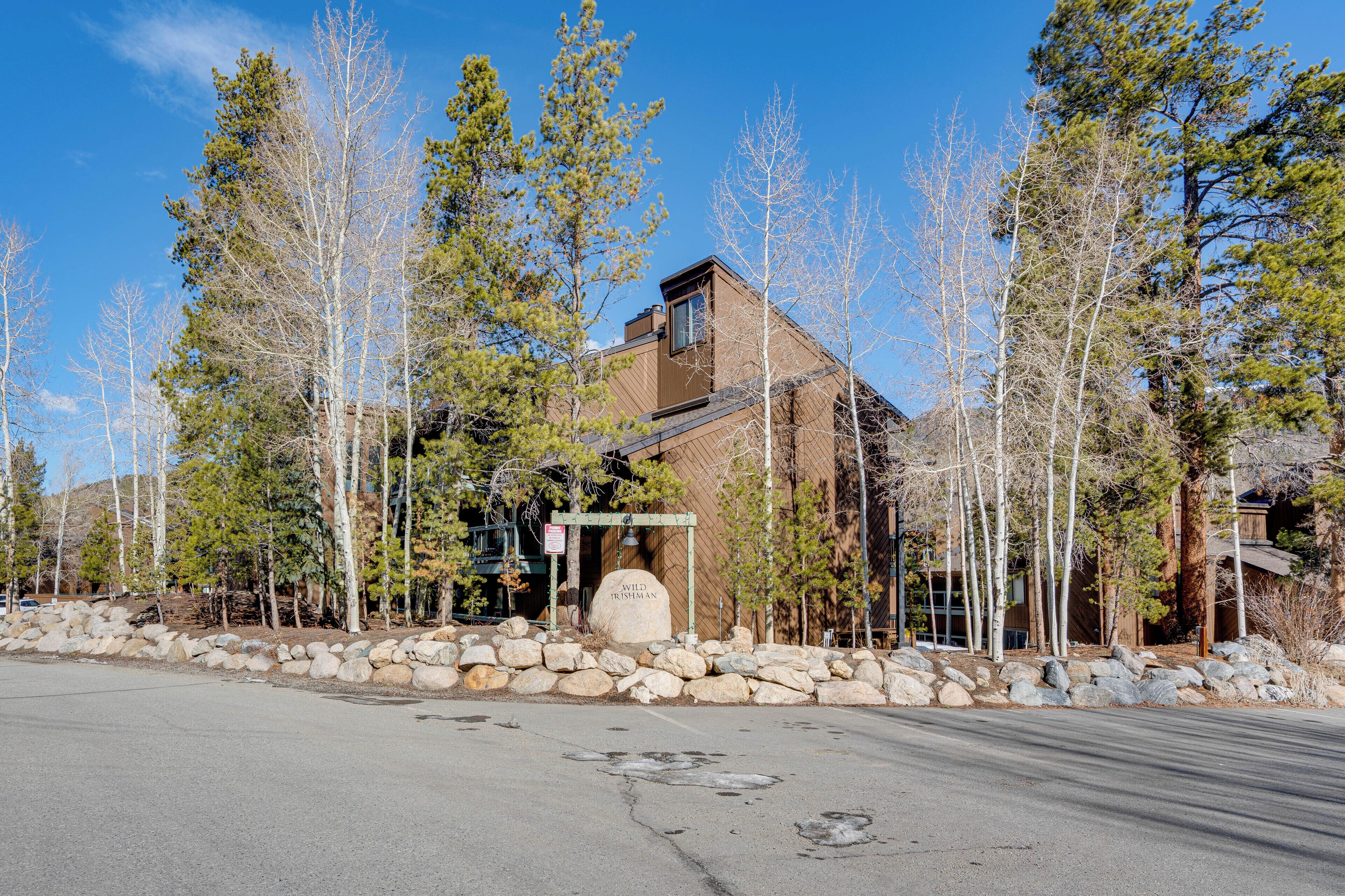 A building with a stone facade, a large rock at the entrance, and trees surrounding it.