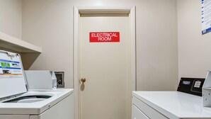Ein Waschraum mit einem Schild, das ihn als Technikraum kennzeichnet, einer Waschmaschine und einem Trockner.