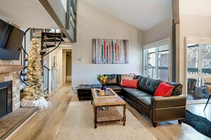A modern living room with a fireplace, a staircase, a leather sofa, and a large window. - 3 Mi to Keystone Resort: Updated Condo w/ Balcony! (Keystone)