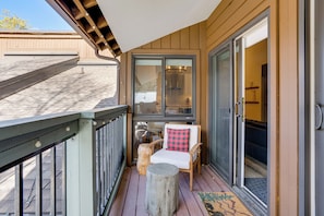 A wooden deck with a glass door leading to a room, a chair with a checkered pillow, and a wooden stump. - 3 Mi to Keystone Resort: Updated Condo w/ Balcony! (Keystone)