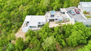 An aerial view of a modern house with a swimming pool, a carport, and lush greenery surrounding it. - Modern vacation home with whirlpool surrounded by greenery (Crikvenica)