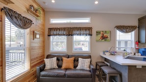 A cozy living area with a sofa, a small kitchen island, and a window with blinds. - Rodeo Thrills & Backyard Bbqs! Lake Wales Retreat (River Ranch)