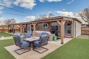 A covered patio area with a table and chairs, a sofa, and a grill.
