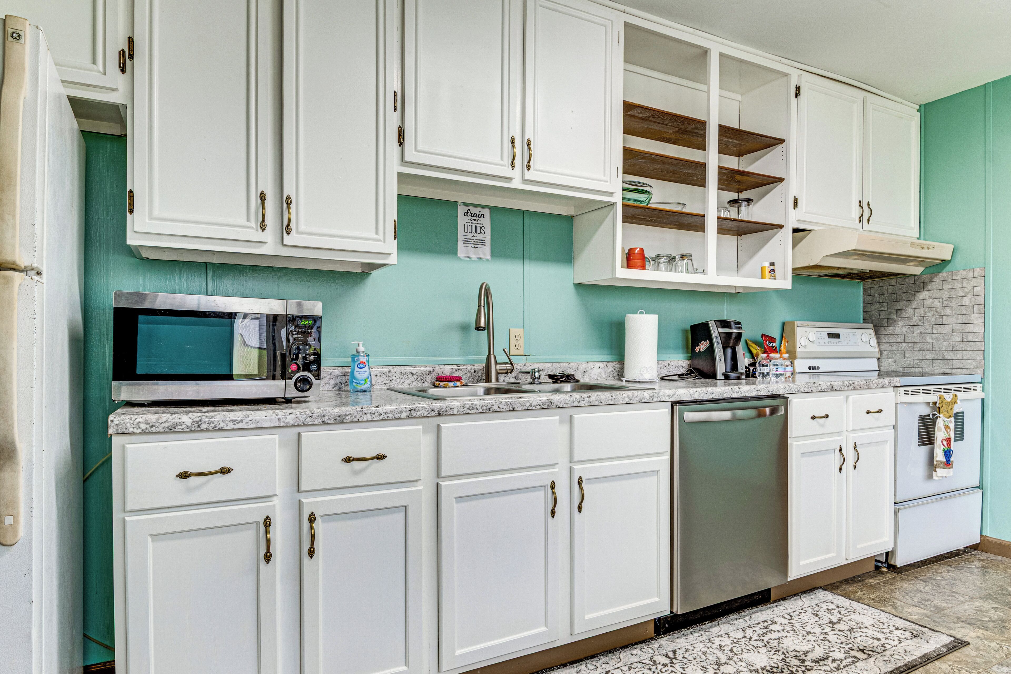 A kitchen with white cabinets, a microwave, a dishwasher, and a stove.