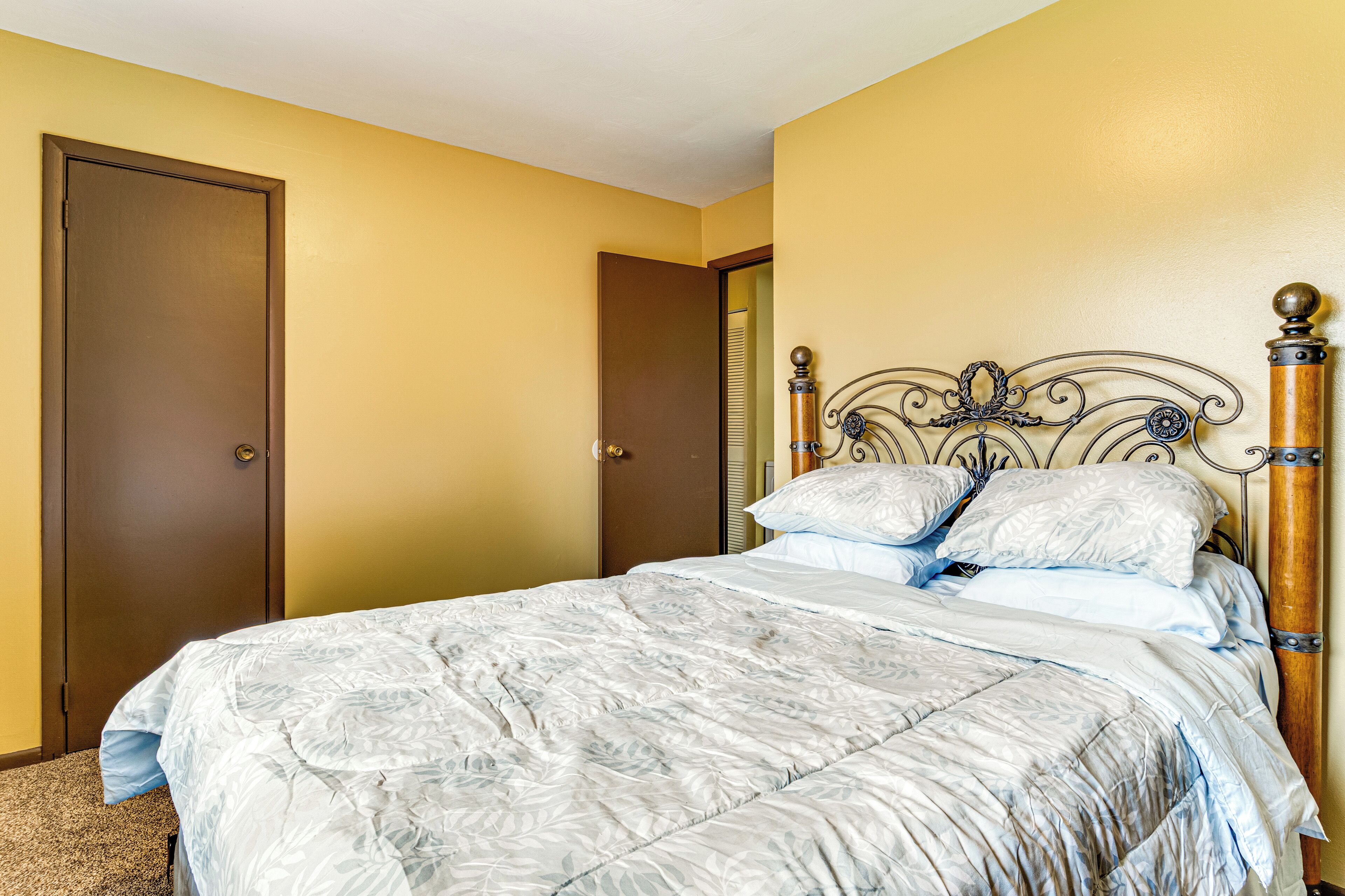 A bedroom with a bed, a wooden door, and a wall with a decorative headboard.