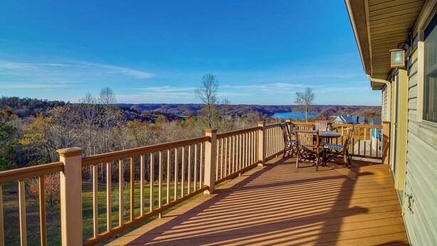 A wooden deck with a railing, a table, and chairs, overlooking a scenic landscape with trees and a body of water. - Byrdstown Apartment < 4 Mi to Dale Hollow Lake! (Byrdstown)