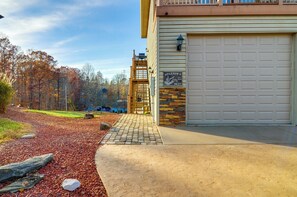 A residential garage with a stone and wood exterior, a metal gate, and a driveway leading to a house. - Byrdstown Apartment < 4 Mi to Dale Hollow Lake! (Byrdstown)