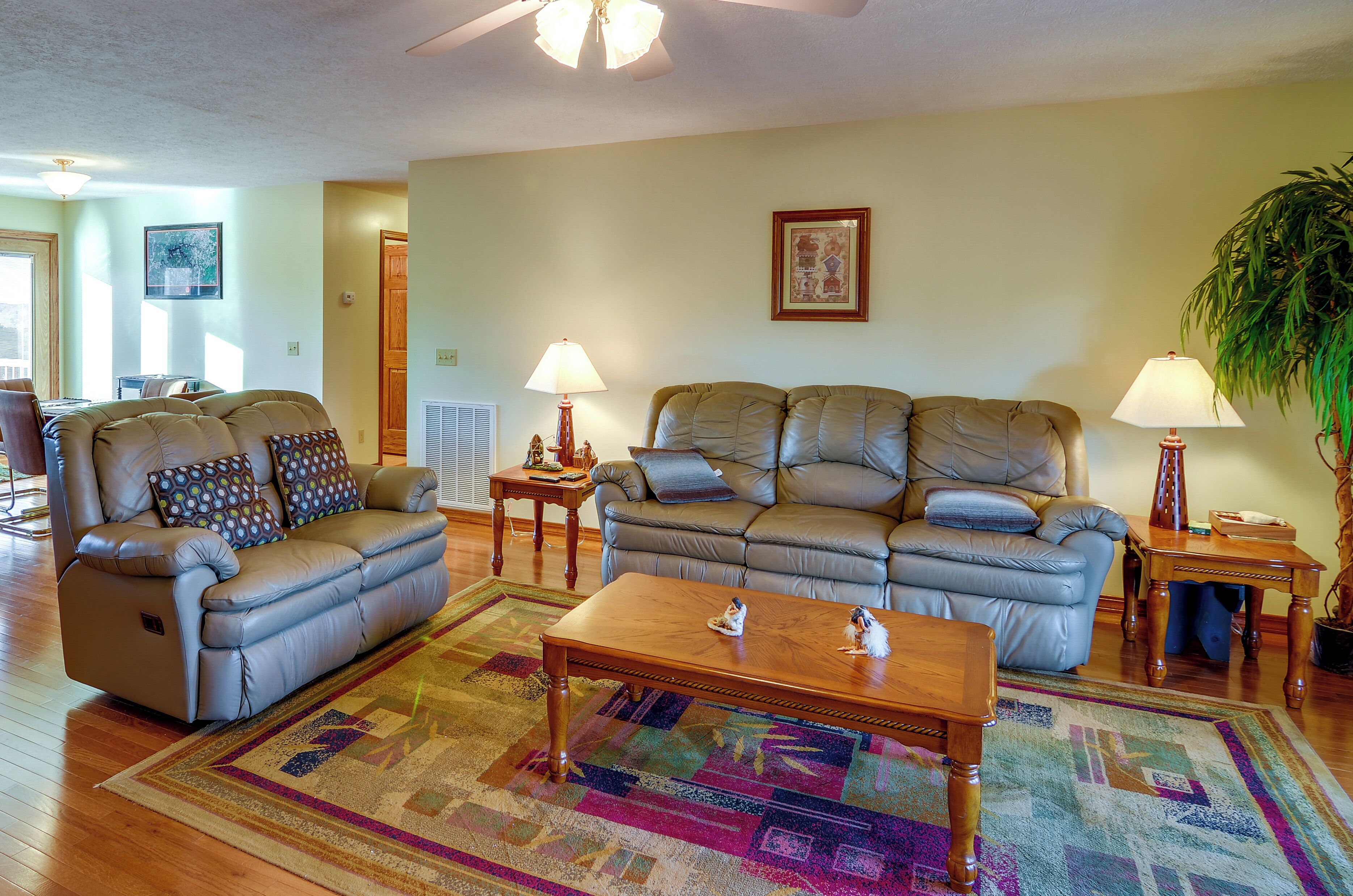 A living room with two leather sofas, a wooden coffee table, and a colorful rug.