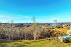 A rural landscape with a clear sky, a grassy field, and a distant body of water.