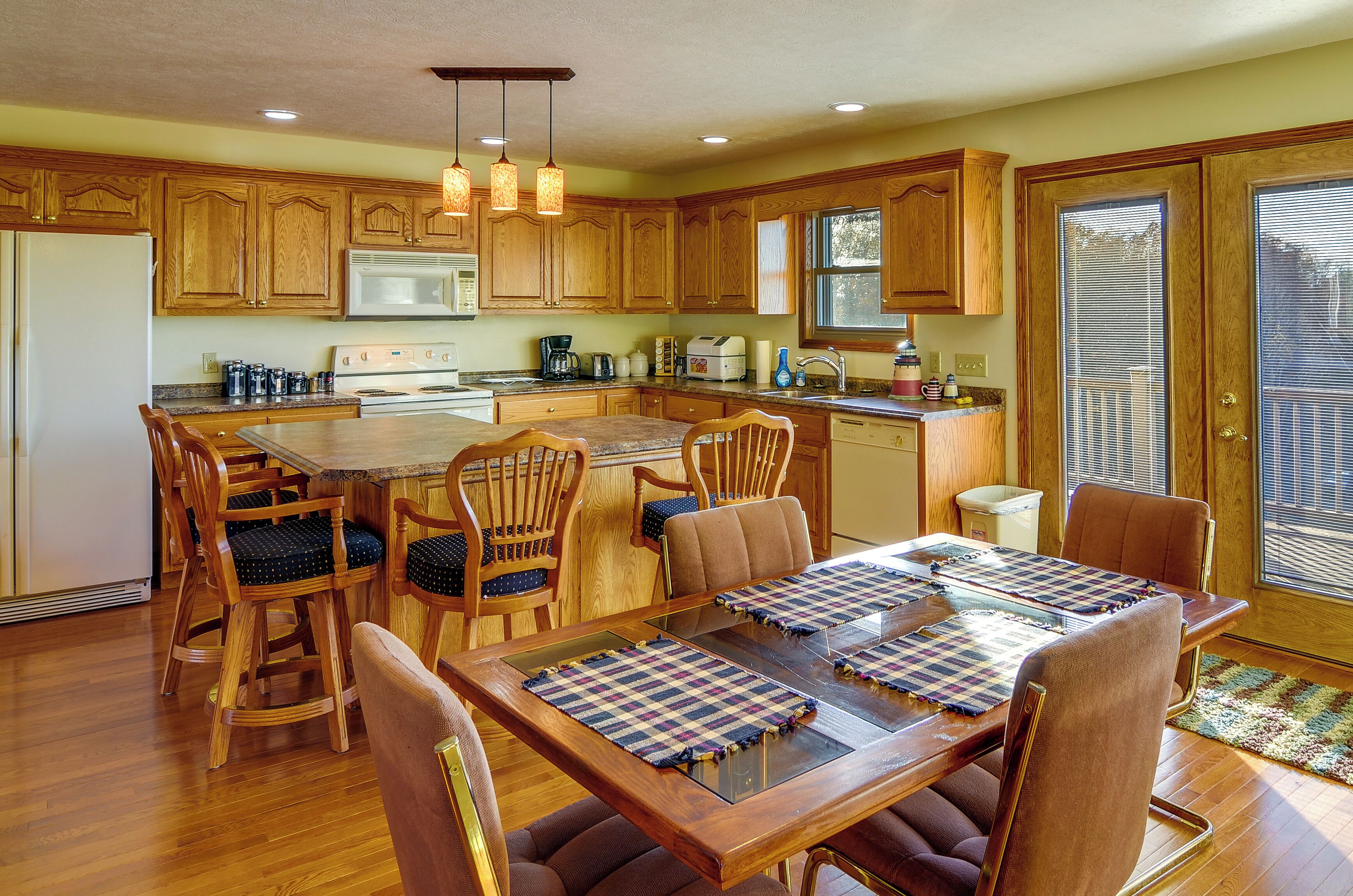 A spacious kitchen with wooden cabinets, a central island, and a dining area with a table set for four.