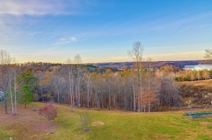 A landscape view with a grassy field, trees, and a distant lake.