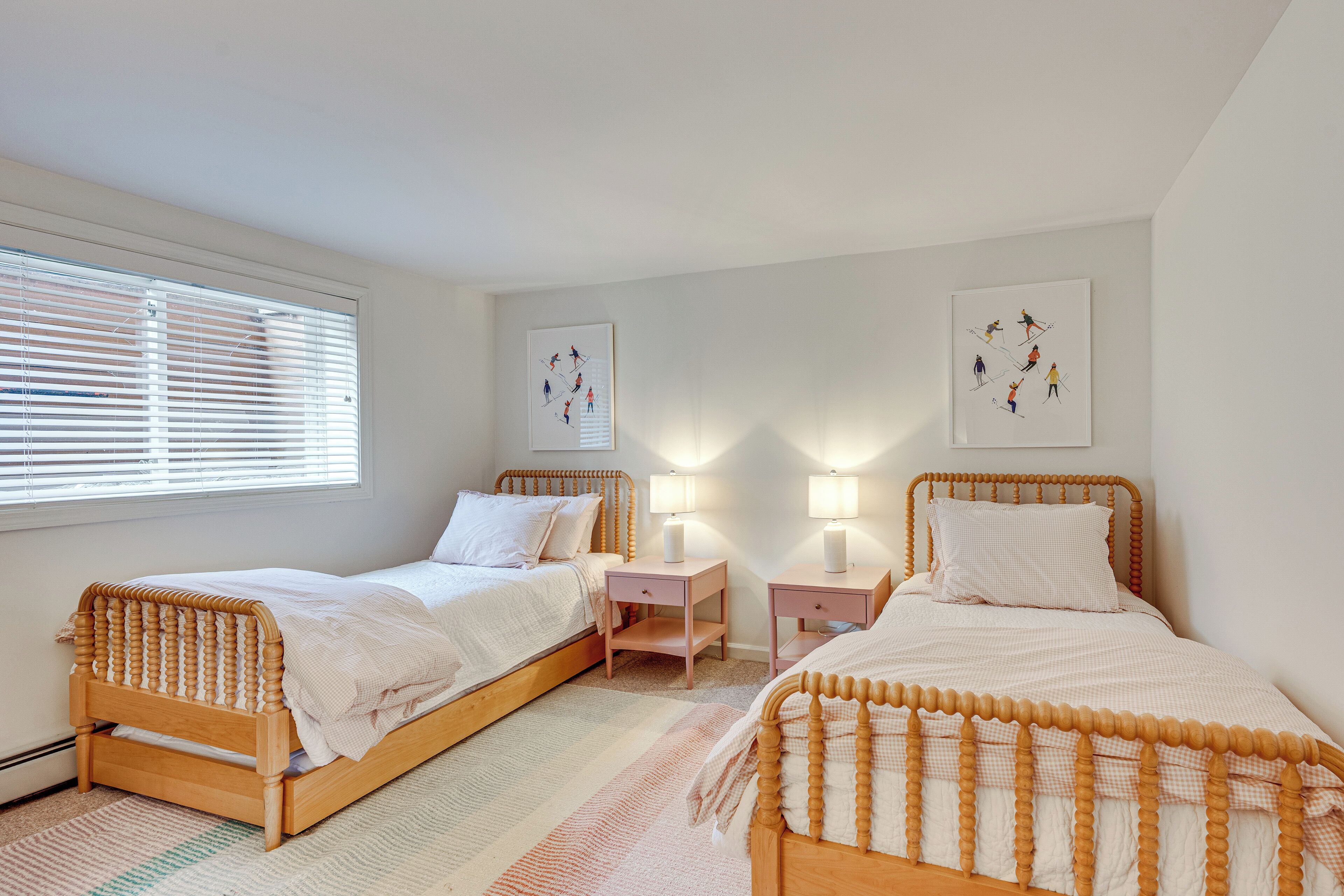 Une chambre à coucher avec deux lits en bois, des tables de chevet et des œuvres d’art murales.
