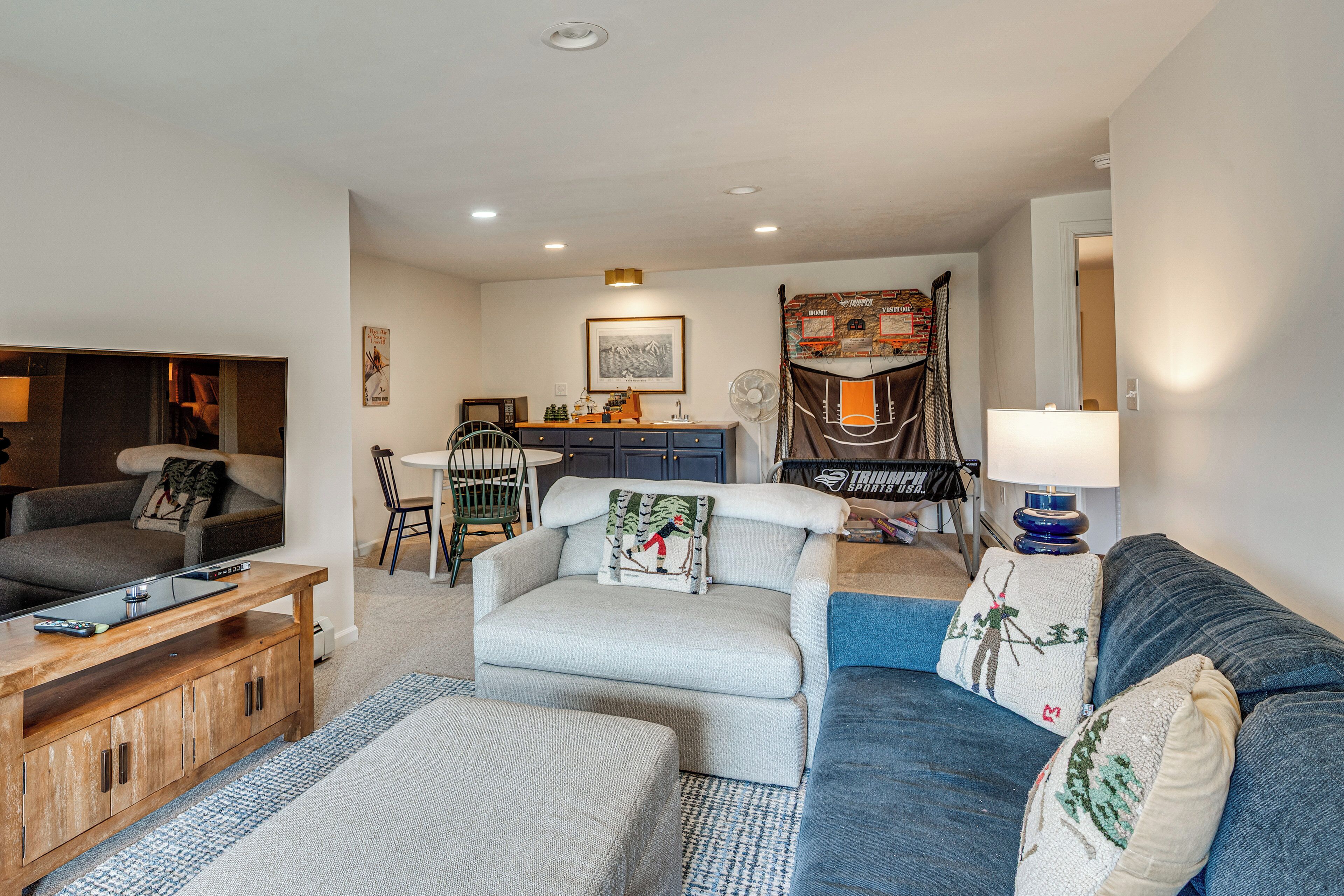 A living room with a sofa, a coffee table, a TV, and a dining area with chairs and a table.