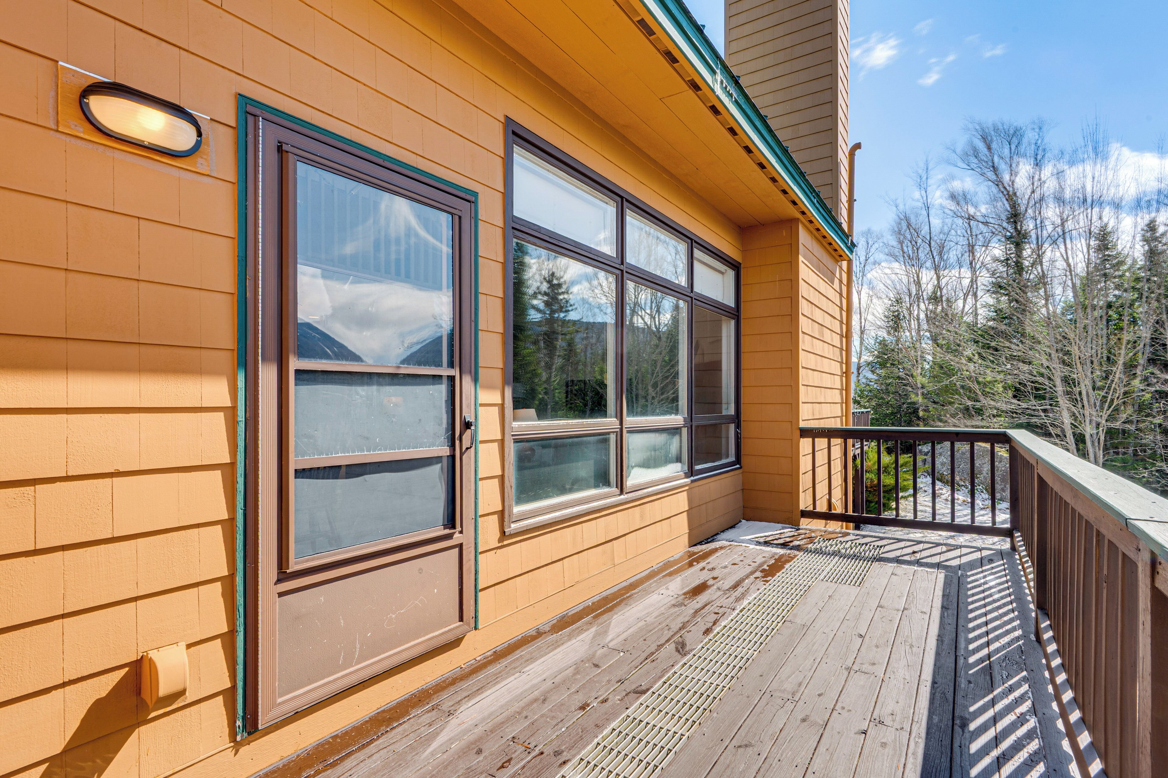 A wooden building with large windows, a wooden deck, and a metal railing.