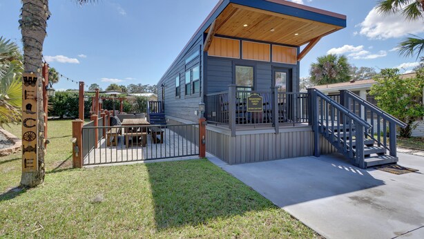 A modern two-story building with a wooden deck and a staircase.