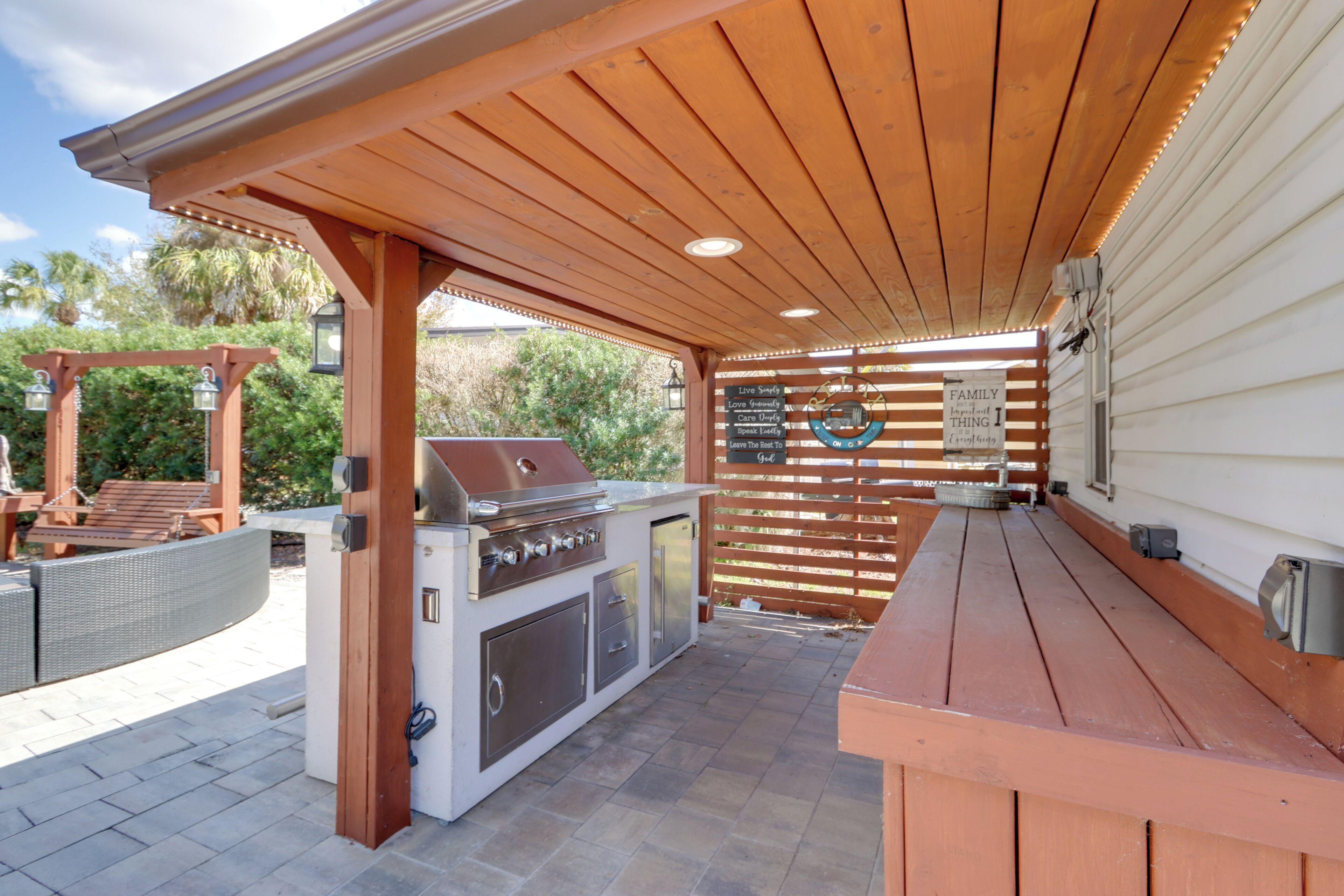 Un patio al aire libre con una parrilla, una pérgola de madera y una mesa de madera.