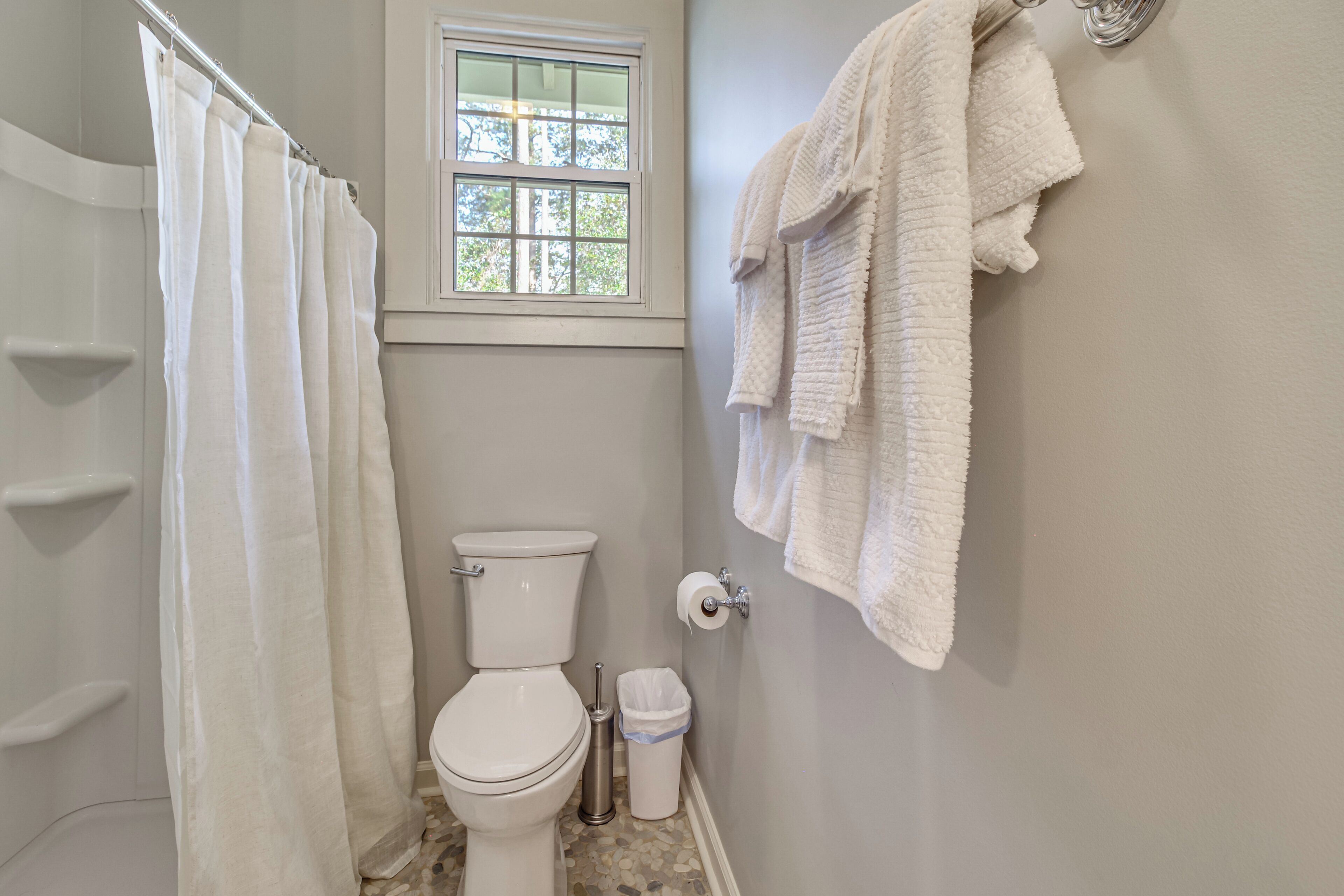 Une salle de bain avec un rideau de douche, des toilettes et des serviettes rangées sur un porte-serviettes.