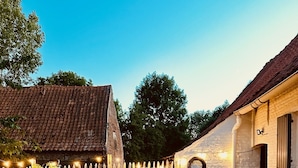 A patio with a barbecue grill, a long wooden table, and chairs. - Renovated, charming heritage farmhouse in the heart of the Flemish Ardennes (Oudenaarde)