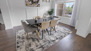 Un comedor con una mesa de madera oscura, sillas color beige, un tapete estampado y una araña.