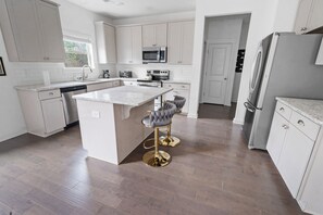 A modern kitchen with white cabinetry, stainless steel appliances, and a central island with bar stools. - Close to Airport/Private Patio/Full kitchen (Atlanta)