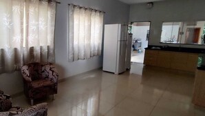 A living room with a patterned armchair, a sofa, a refrigerator, and a kitchen area with a counter and cabinets. - Each spacious exit leads to technoshow. (Rio Verde)