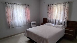 A bedroom with a bed, nightstands, a heater, and curtains. - Each spacious exit leads to technoshow. (Rio Verde)