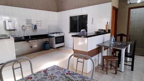A compact kitchen with white tiles, a gas stove, a sink, and a dining area with a table and chairs. - Each spacious exit leads to technoshow. (Rio Verde)