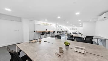 Een moderne vergaderzaal met een lange tafel, meerdere stoelen en een potplant.